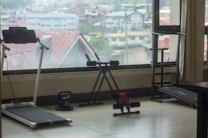 A gym with exercise equipment including a treadmill, weights, and a bench. - ZB Suites Baguio ZBBI (Baguio)