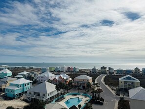 A coastal resort with colorful buildings, a swimming pool, and a view of the ocean. - Indies 406 | 1BR/1BA Gulf-View Condo | Sleeps 4 | Balcony & Pool Access (GULF SHORES)