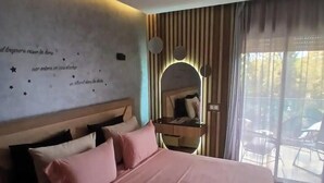 Een hotelkamer met een groot bed, een nachtkastje, een spiegel en uitzicht op het omliggende landschap.