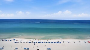 A beach with clear blue water, white sand, and blue umbrellas. - Gulf-Front Sunrise Beach Resort | Family Favorite | Sleeps 8 | Near Pier Park (Panama City Beach)