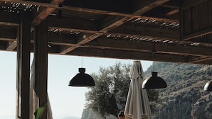 An outdoor dining area with wooden beams, potted plants, and a view of mountains. - Klay Hotel Faralya Adults Only (Fethiye)
