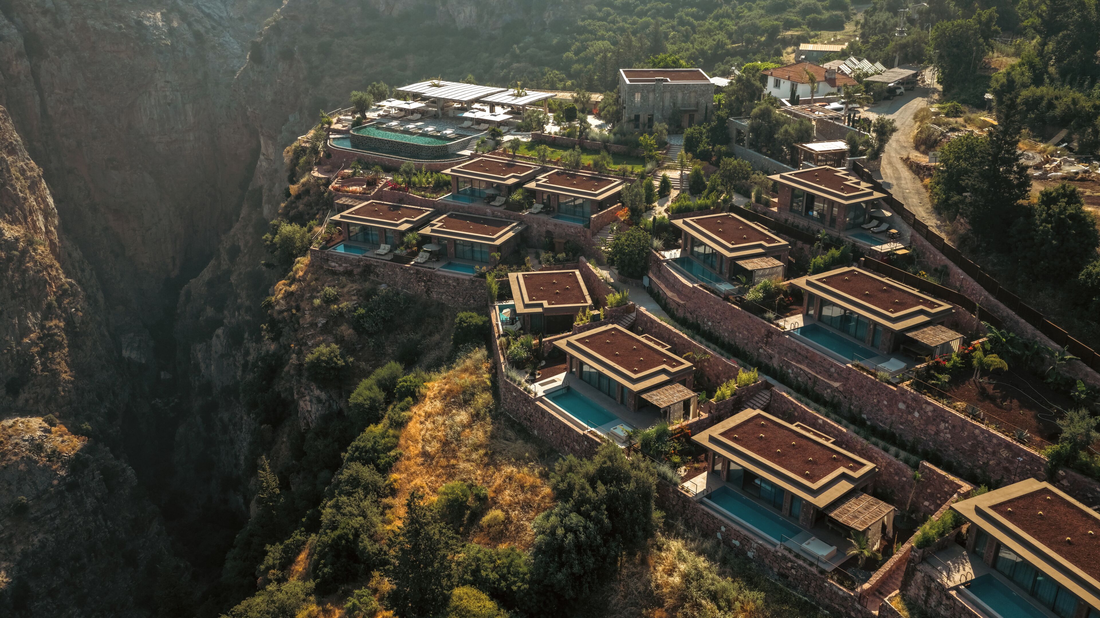 A resort with multiple buildings, a pool, and a canyon backdrop.
