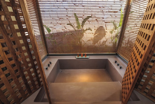 A spa room with a large bathtub, wooden lattice walls, and a small shelf with decorative items. - Klay Hotel Faralya Adults Only (Fethiye)