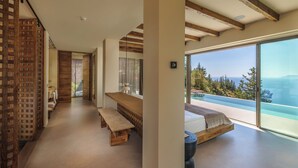A modern interior with a large window, a wooden bench, and a bed. - Klay Hotel Faralya Adults Only (Fethiye)