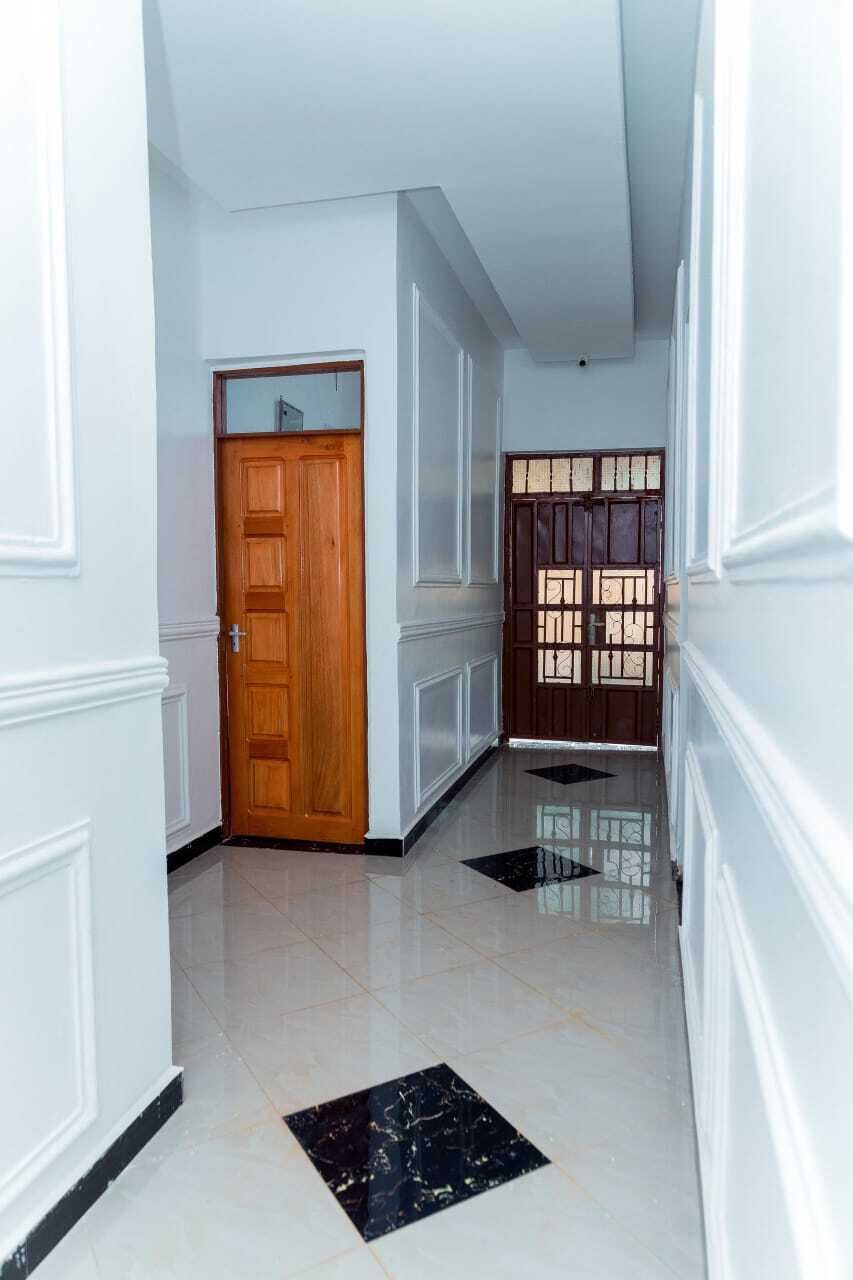 A hallway with white walls, a wooden door, and a glass door with a window.