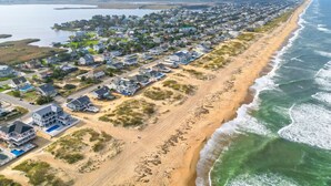 A coastal residential area with houses along the beach, a clear view of the ocean, and a distant body of water. - New / Oceanview / Heated Pool • Steps to Beach (Virginia Beach)