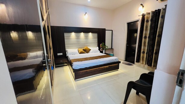A modern bedroom with a large bed, bedside tables, a ceiling fan, and a bathroom with a shower and toilet. - Hotel Green Garden in Ludhiana, Couple friendly Near Railway Station (Ludhiana)