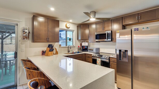 A modern kitchen with wooden cabinets, a stainless steel refrigerator, a microwave, and a coffee maker. - Pool & Patio! Mod Desert Digs Near Lake Havasu (Lake Havasu City)