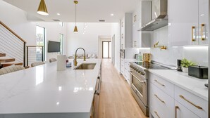 A modern kitchen with white cabinetry, stainless steel appliances, and a central island. - 3 Mi to Naples Beach: Chic Group Getaway w/ Pools! (Naples)