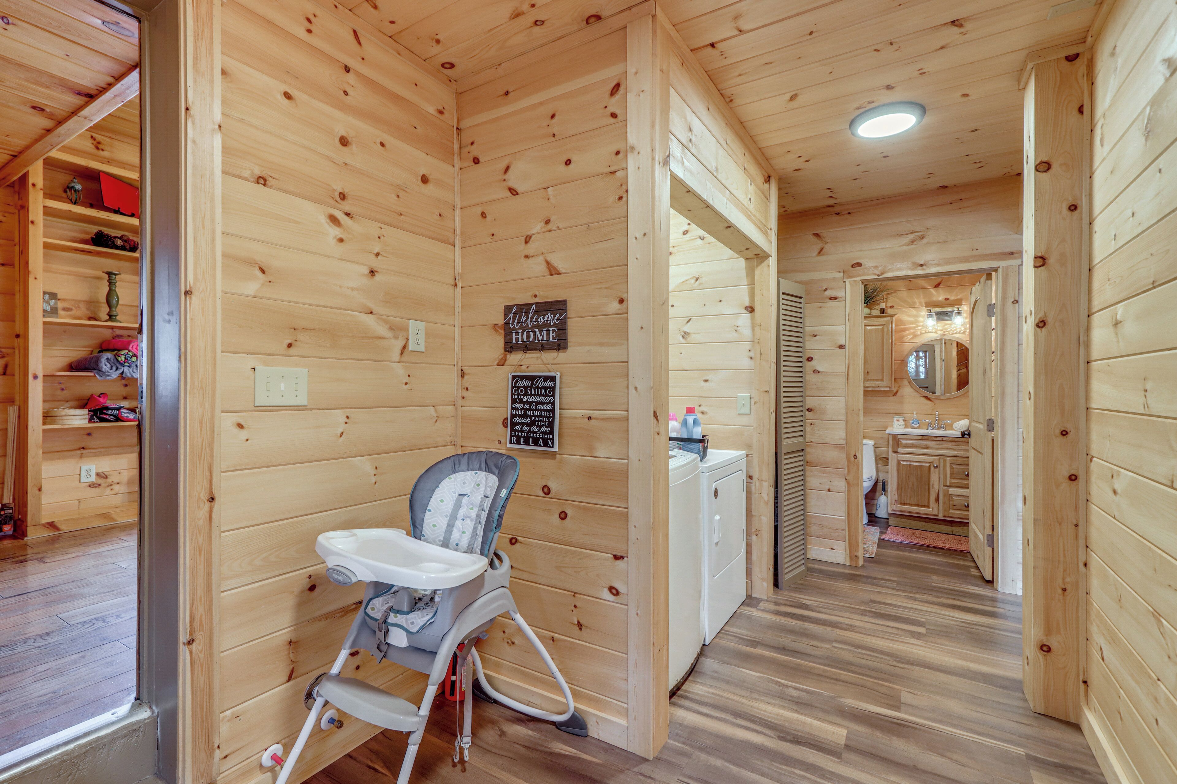 A wooden interior with a baby chair, a welcome sign, and a kitchen area.