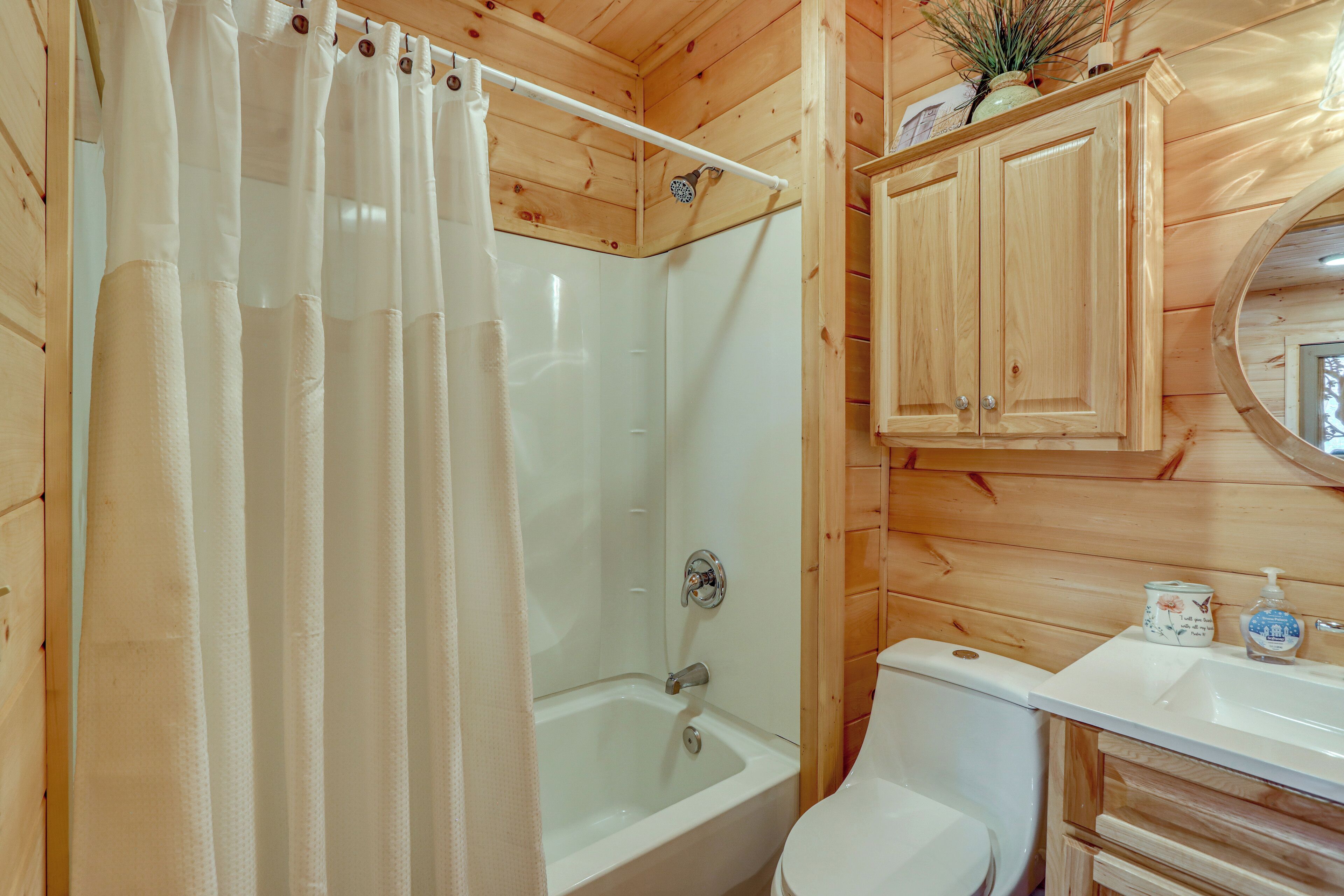 A wooden cabin bathroom with a shower, toilet, and wooden cabinets.