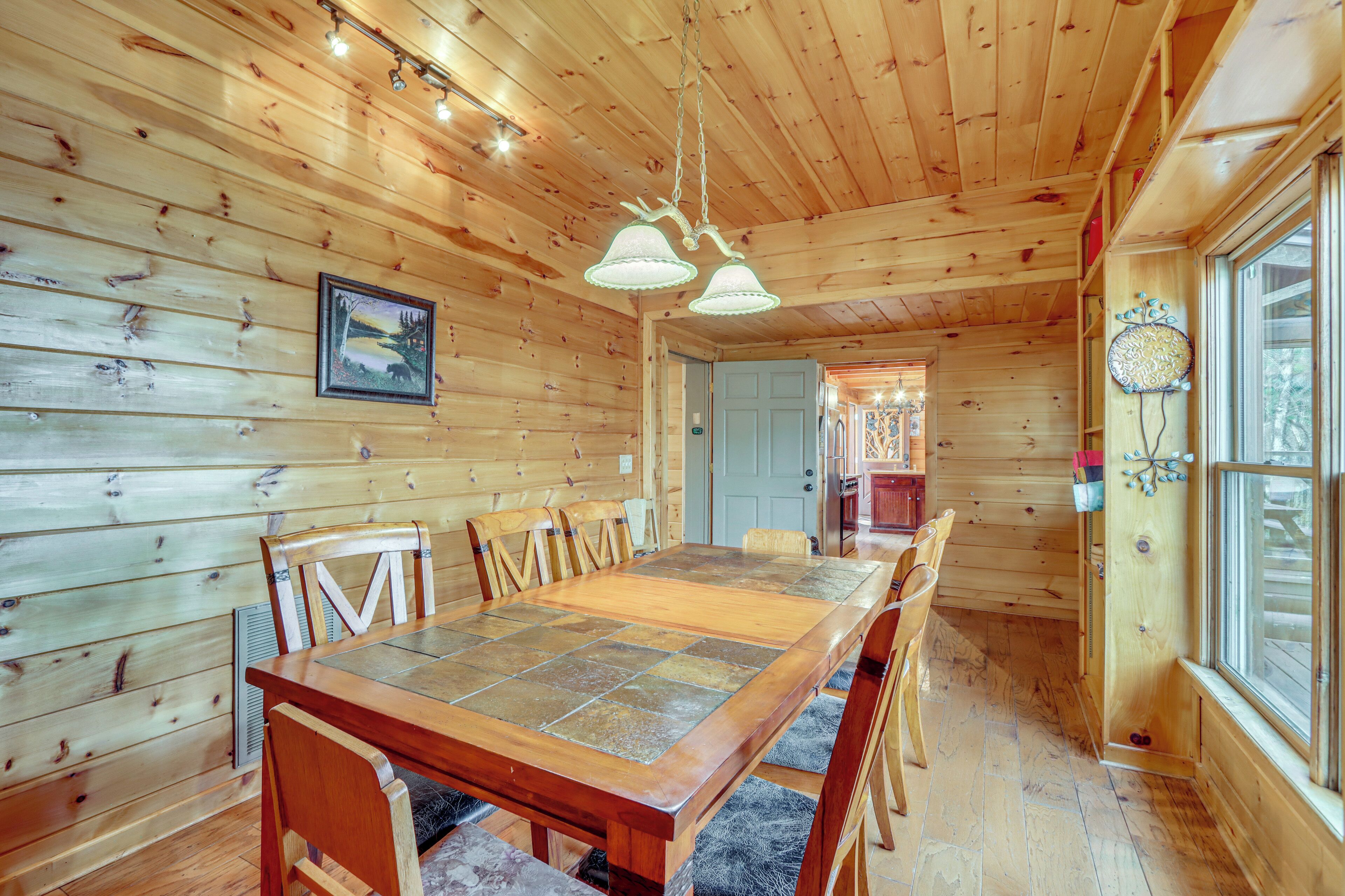 Interior de madera con una mesa de comedor, sillas y una lámpara colgante.