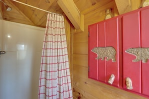 A wooden cabin interior with a shower curtain, a red cabinet with bear carvings, and wooden walls. - Spacious Log Cabin w/ Stunning Views in Blue Ridge (Blue Ridge)