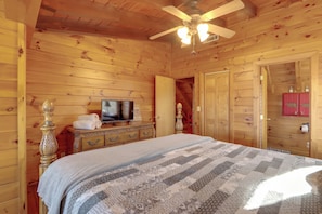 A wooden cabin bedroom with a bed, dresser, television, and a ceiling fan. - Spacious Log Cabin w/ Stunning Views in Blue Ridge (Blue Ridge)