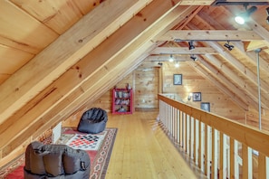 An attic room with wooden beams, a red bookshelf, a black bean bag, and a checkered rug. - Spacious Log Cabin w/ Stunning Views in Blue Ridge (Blue Ridge)