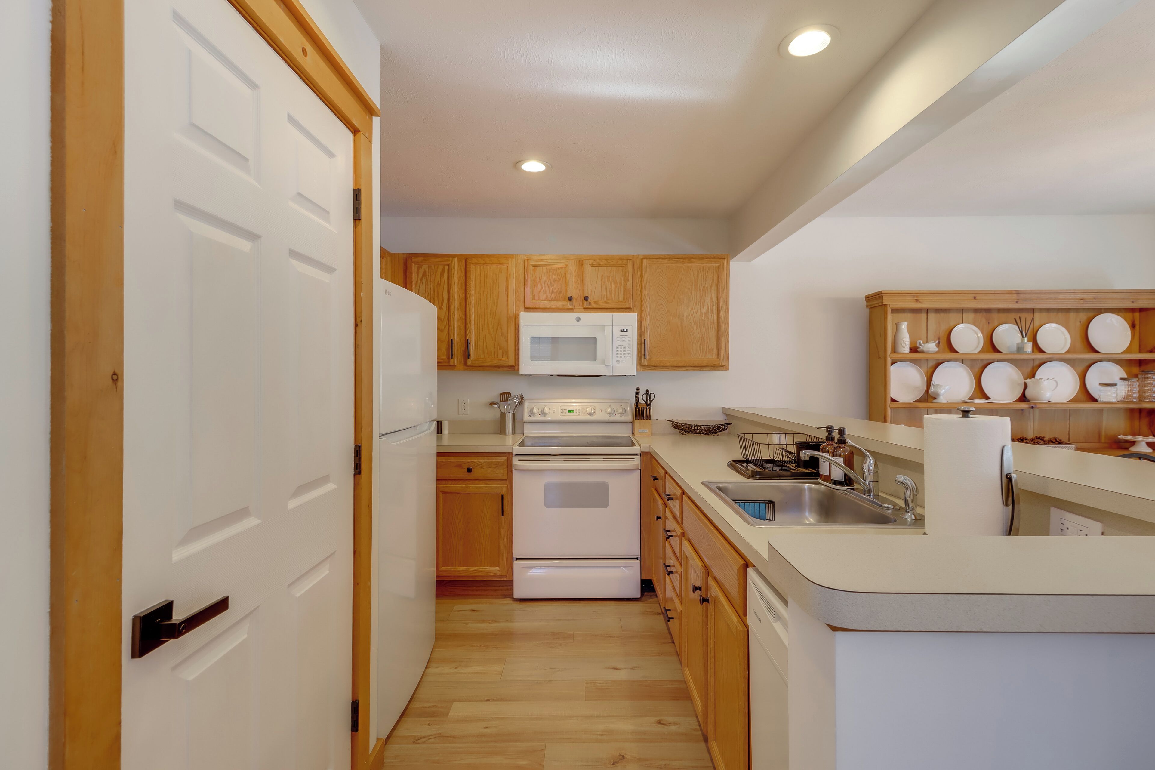 A kitchen with wooden cabinets, a white refrigerator, a microwave, a stove, and a sink.