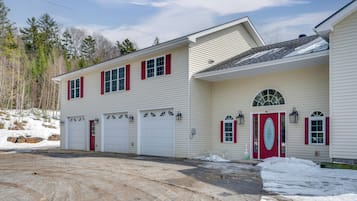 A two-story building with a garage, a red door, and a snow-covered ground.