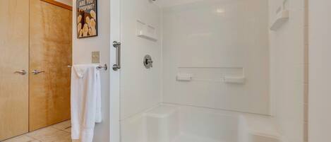 A modern bathroom with a glass-enclosed shower, a wooden door, and a towel rack.