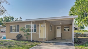 A single-story house with a covered porch, a front door, and a small front yard. - Private Yard & Patio! Tampa Bay Family Getaway (Pinellas Park)
