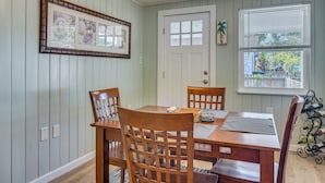 A dining area with a wooden table and chairs, a framed picture on the wall, a door, and a window with a view. - Private Yard & Patio! Tampa Bay Family Getaway (Pinellas Park)
