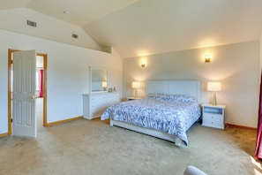 A bedroom with a large bed, two bedside tables, a dresser, and a door leading to another room. - Seaside Eureka Vacation Rental w/ Bay Views! (Eureka)