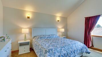 A bedroom with a bed, two bedside lamps, a nightstand, a dresser, and a window with curtains.