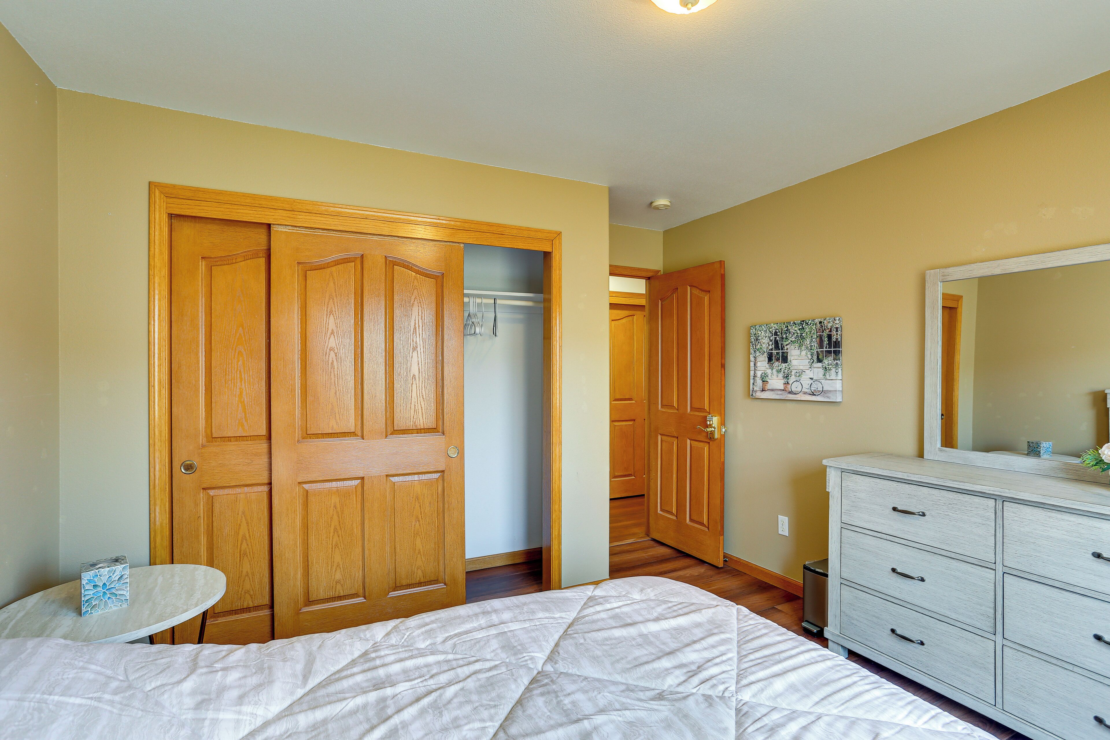 Un dormitorio con cama, cómoda, espejo y puertas de madera.