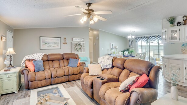 A living room with two brown leather sofas, a ceiling fan, and a kitchen area in the background. - Nina's Beach Retreat: ~ 1 Mi to Holden Beach! (Supply)