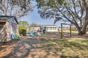 A backyard with a swing set, a shed, and a house. - Nina's Beach Retreat: ~ 1 Mi to Holden Beach! (Supply)