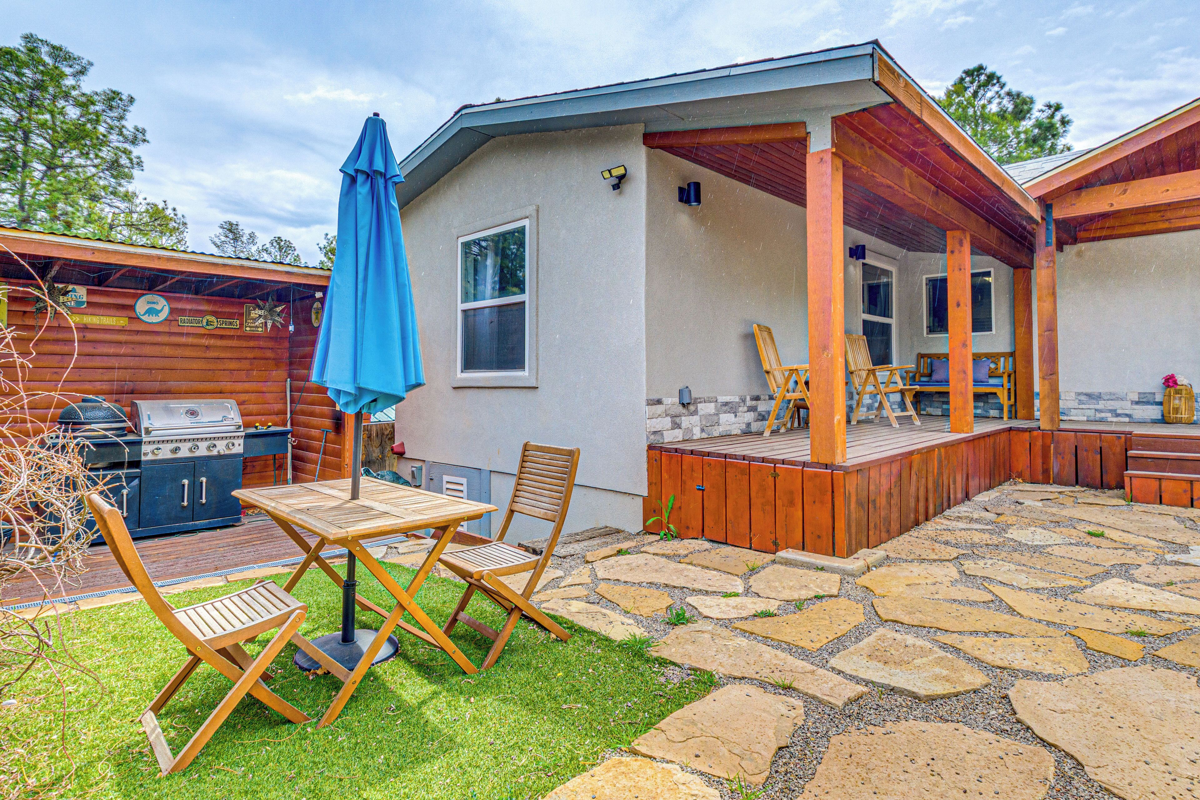 A backyard with a patio, a grill, and a covered seating area.