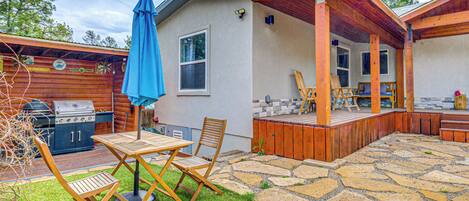 A backyard with a patio, a grill, and a covered seating area.