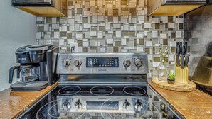 A kitchen with a Samsung stove, a Keurig coffee maker, and a tiled backsplash.