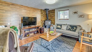 A living room with a TV, fireplace, sofa, and wooden wall.