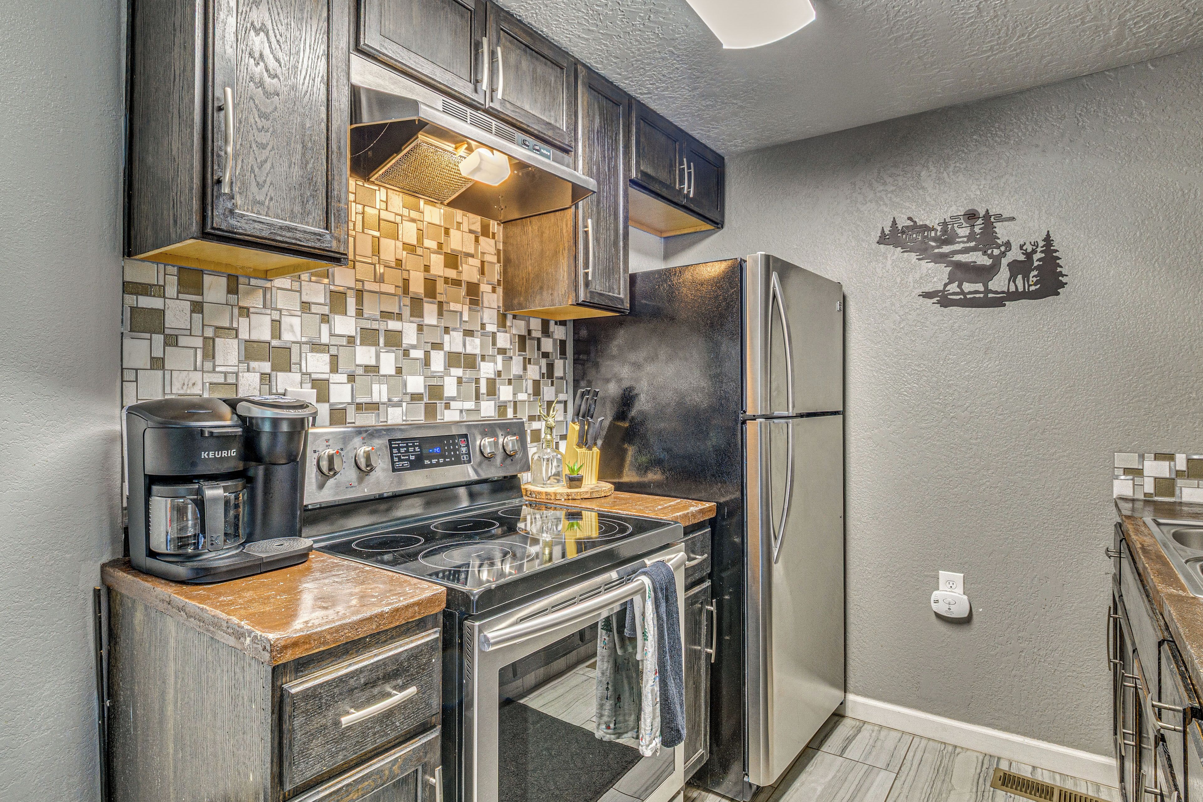 A kitchen with a stove, coffee maker, and refrigerator.