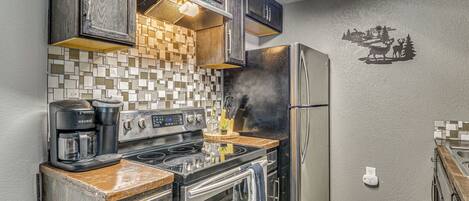 A kitchen with a stove, coffee maker, and refrigerator.