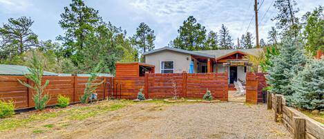 A rustic cabin with a gravel driveway, wooden fences, and a small porch.