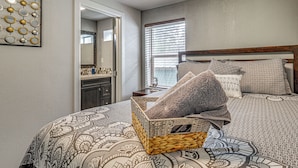 A bedroom with a patterned bedspread, a wooden headboard, and a woven basket on the bed.