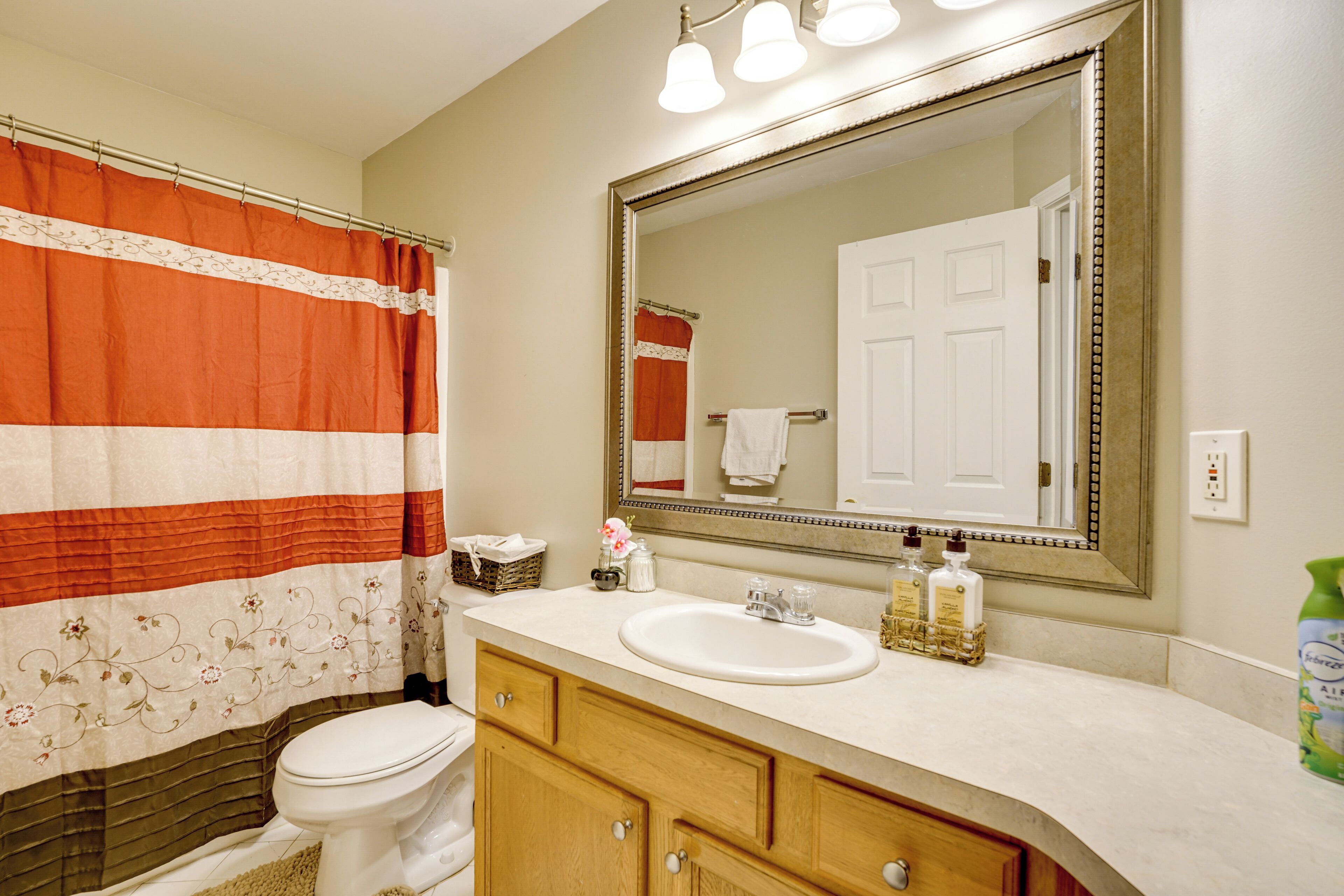 A bathroom with a toilet, sink, and mirror.