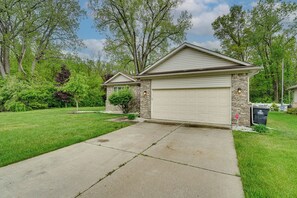 A two-car garage attached to a house with a brick foundation and a sloped roof. - Pets Welcome: Convenient Family Home in Westland! (Westland)