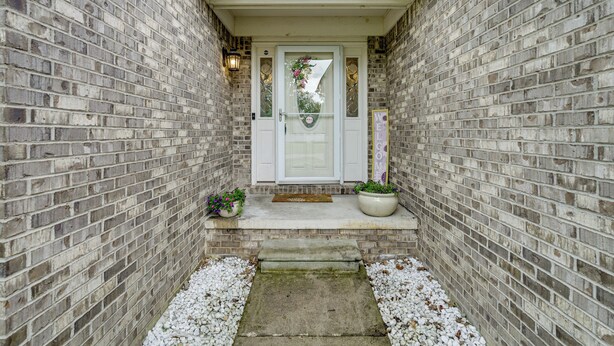 A brick house with a white front door, a small porch, and a skylight above. - Pets Welcome: Convenient Family Home in Westland! (Westland)