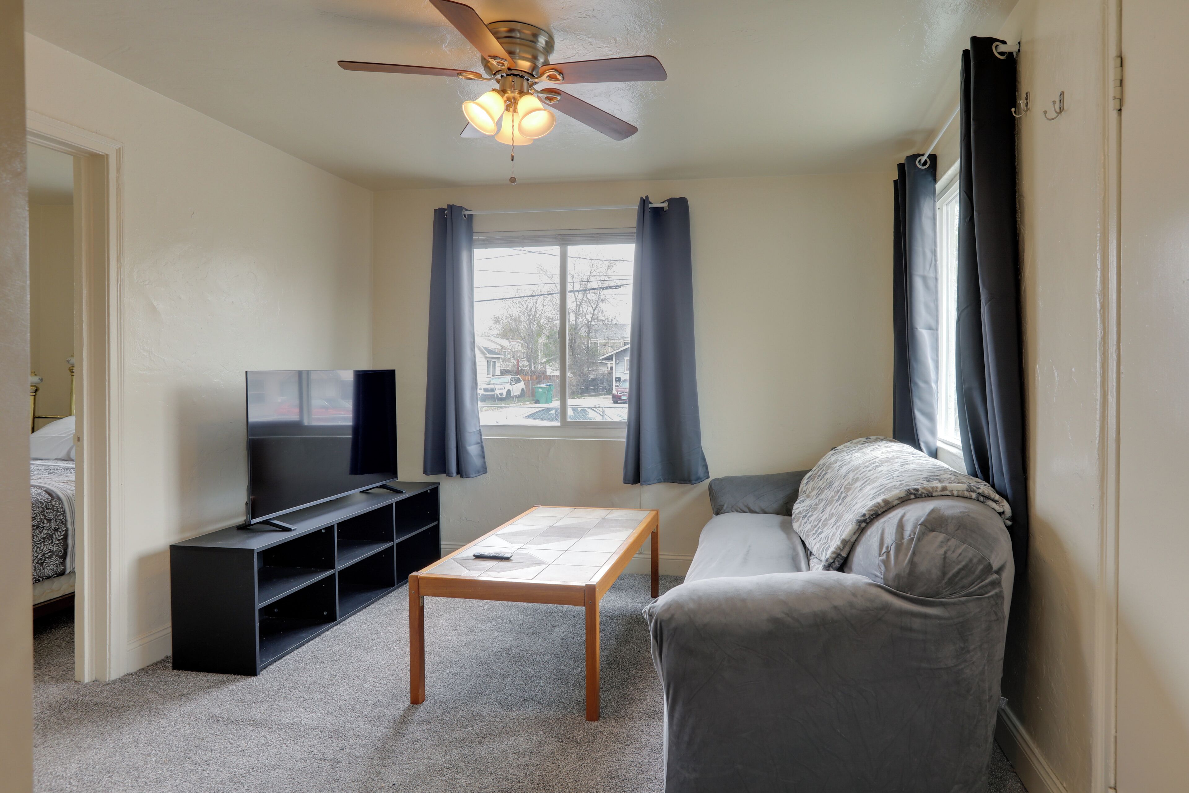 Ein Wohnzimmer mit Fernseher, Sofa, Couchtisch und Deckenventilator.