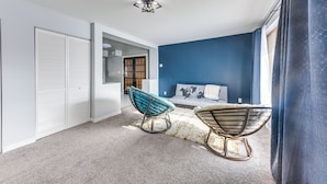 Une chambre à coucher avec un lit, deux fauteuils à bascule, une armoire et un luminaire au plafond.