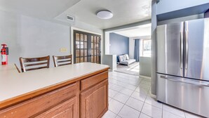 Une cuisine moderne dotée d’un réfrigérateur en acier inoxydable, de meubles en bois et d’un grand îlot central.