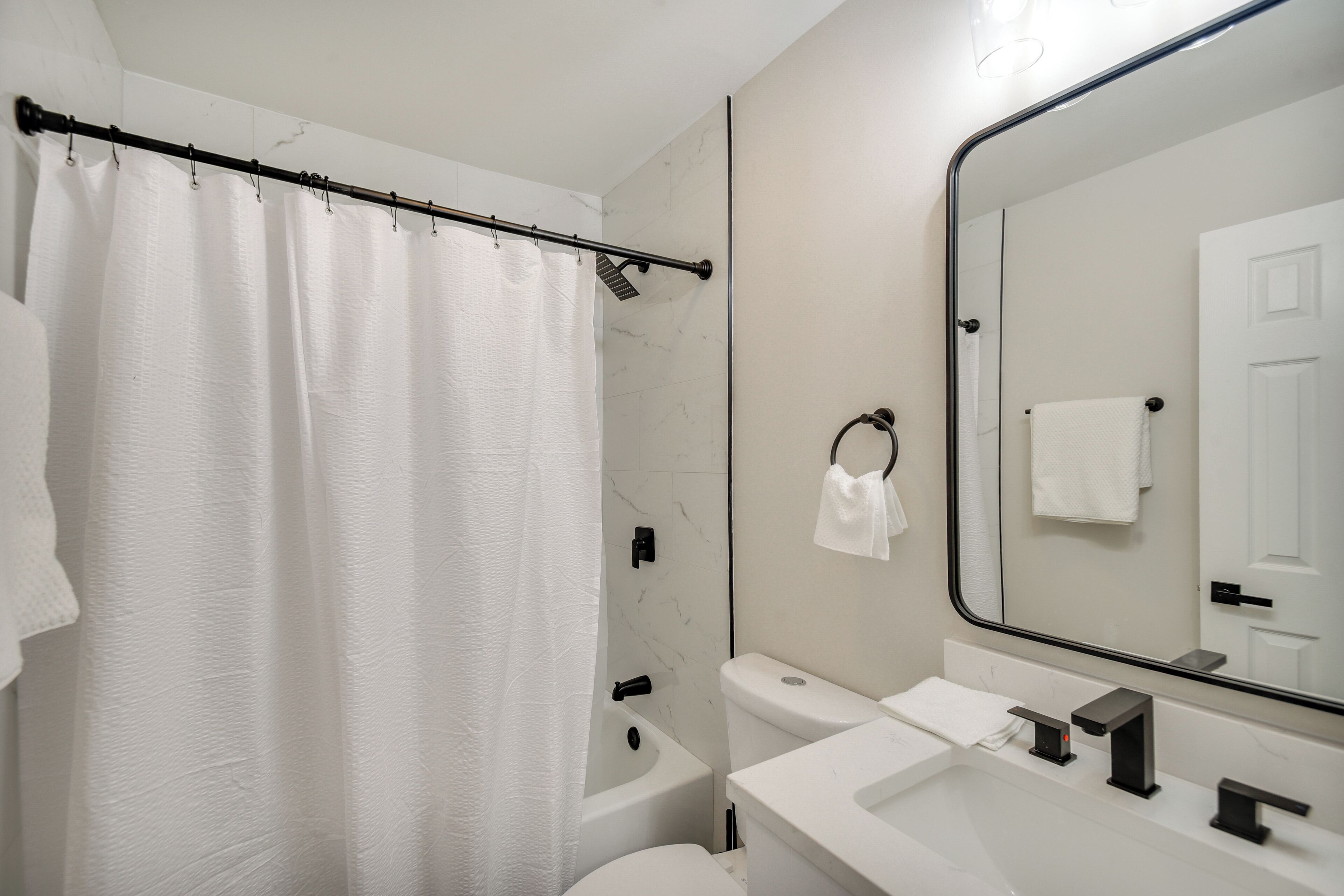 Une salle de bain avec une baignoire, des toilettes, un lavabo et un grand miroir.