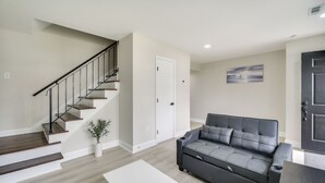 A living room with a staircase, a gray sofa, and a white coffee table. - Near Waterfront! Retreat 6 Mi to Hampton Coliseum (Newport News)
