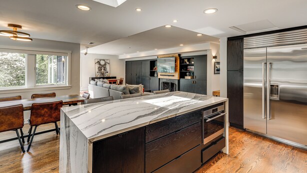 A modern kitchen with a marble island, dark cabinetry, and a stainless steel refrigerator. - Modern Broadway Luxury: Spacious Seattle Home! (Seattle)