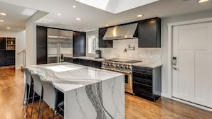 A modern kitchen with a central island, dark cabinetry, stainless steel appliances, and a skylight. - Modern Broadway Luxury: Spacious Seattle Home! (Seattle)