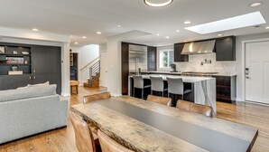 A modern kitchen with a dining area, built-in cabinets, and a staircase leading to another level. - Modern Broadway Luxury: Spacious Seattle Home! (Seattle)