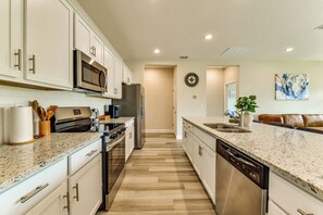 A modern kitchen with stainless steel appliances, a dishwasher, and a countertop with a speckled pattern.
