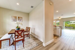 Un comedor con una mesa de madera, sillas, un banco y un jarrón decorativo.